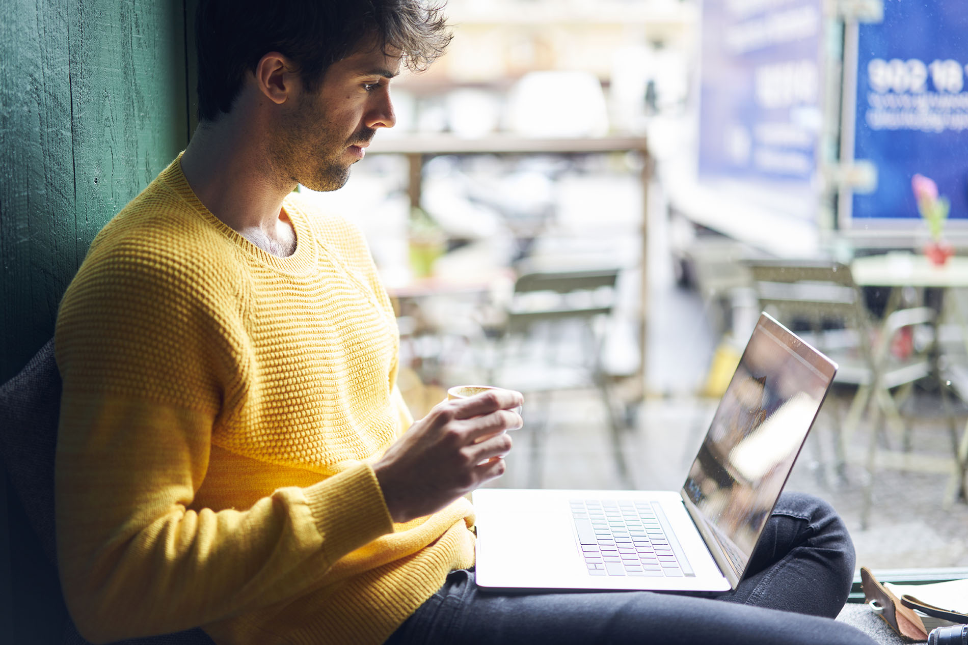 Ragazzo che guarda pc in un caffè